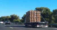 Transporte de dimensiones especiales. Un camión transportando palés por una autovía.