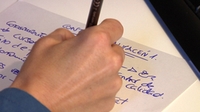 Una mano escribiendo sobre un papel en blanco.