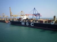 Mercante con gran cantidad de contenedores descargando en el puerto de Valencia, se observan varios puentes grúas trabajando en la descarga, Más al fondo se observa otro mercante en la misma situación.
