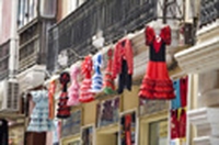 Fachada de una tienda de trajes de sevillana, con unos cuantos trajes de sevillana colgados de la fachada.