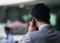 Un hombre de espaldas con chaqueta habla por teléfono en la calle. Sólo se observa la parte superior del hombre.