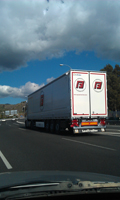 Un camión de mercancías circulando por una autovía. El camión se observa de atrás hacia adelante.