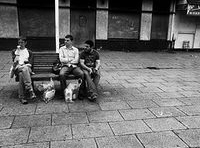 Argument. Imagen en blanco y negro de tres chicos sentados en un banco que parece que están discutiendo por algo.