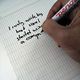 Mano con un lápiz cogido escribiendo sobre un papel.