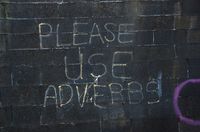 Adverbs. Mensaje en inglés escrito en blanco sobre un fondo negro: 'Please use adverbs'.