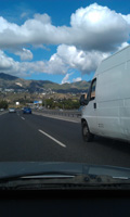 Furgoneta de transporte blanca circulando por una autovía, fotografiada desde un vehículo.