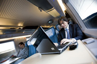 Se ve a un comercial trabajando en un portátil mientras se desplaza en tren, previsiblemente, a visitar a un cliente. 