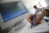 Un/a trabajador/a está tomando notas de la información que aparece en pantalla. 