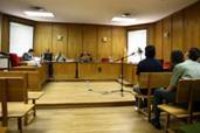 Celebración de un juicio oral. Imagen que muestra un juzgado en el que se está celebrando un juicio oral. El juez está sentado detrás de un escritorio en el estrado, y en frente de él, están sentadas las personas que asisten al juicio.