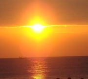 Ilustración de una puesta de sol en el mar con un barco a lo lejos.