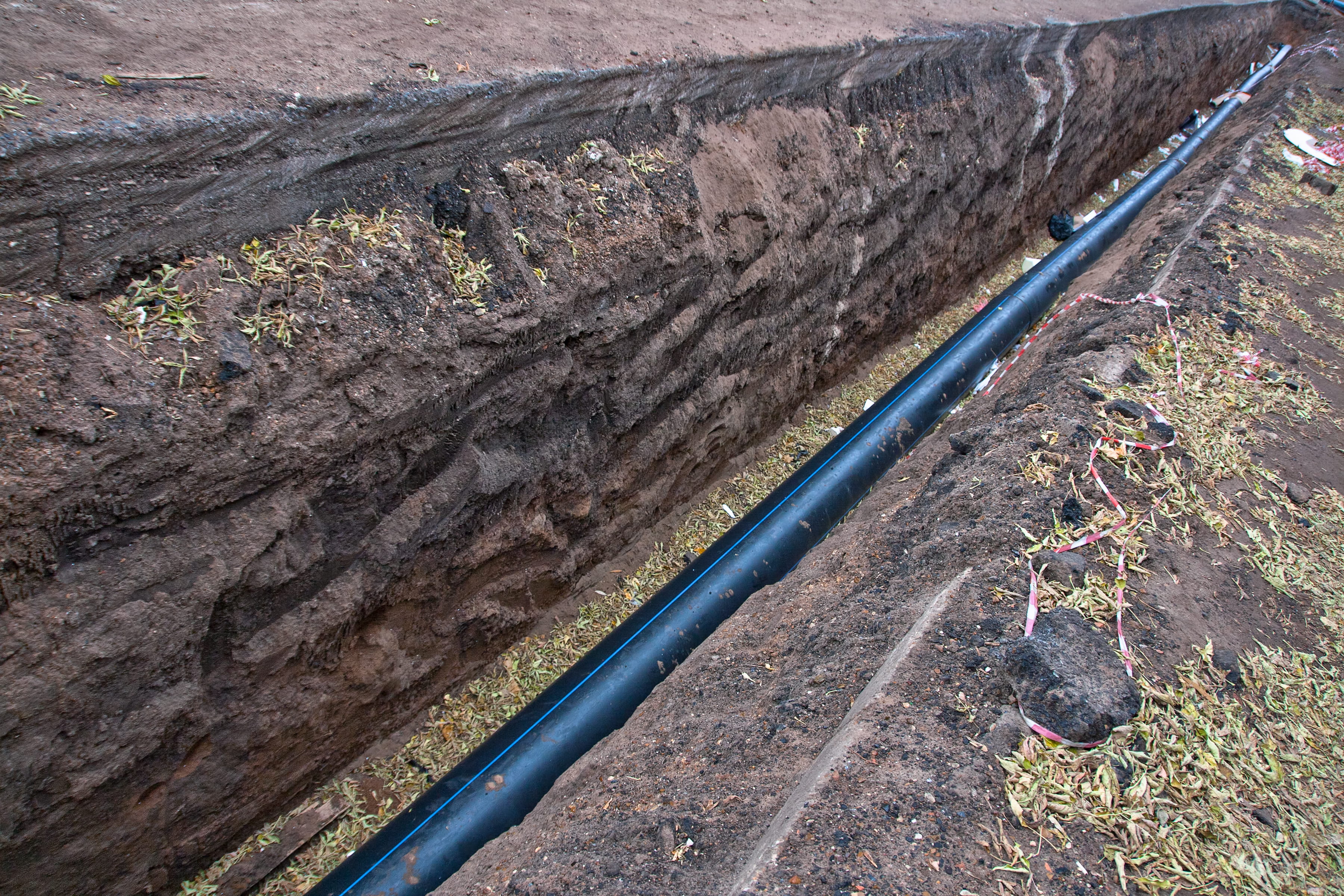 Tubería plástica de suministro de agua. Ilustración de una zanja con una tubería plástica de suministro de agua
