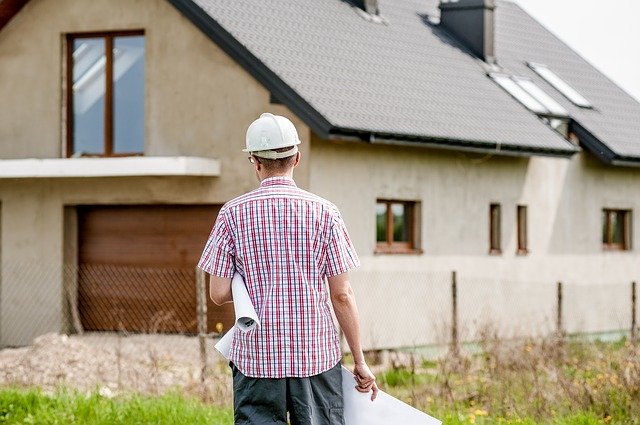 Ilustración de una persona con casco de obra acercándose a una casa en construcción.