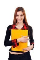 Estrella. Imagen de Estrella, una chica joven, pelo castaño, viste chaqueta y pantalón negro, con una carpeta amarilla cerrada.