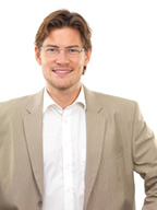 Imagen de Lorenzo, chico joven, rubio, con gafas, chaqueta gris claro y camisa blanca.