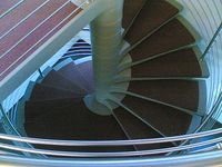 Fotografía que muestra la perspectiva superior de una escalera de caracol. La escalera de caracol es aparentemente metálica.