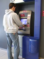 Fotografía en la que aparece Luis de espaldas frente a un cajero automático, sacando dinero del mismo.