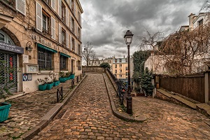 Imagen de una calle con calzada y acera adoquinada.