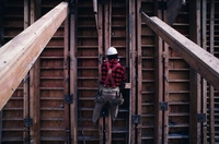 Imagen de un hombre colgado con un arnés de una estructura de madera.