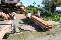 Imagen que muestra a unos hombres moviendo unos tablones de madera.