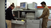 Imagen que muestra a dos operarios en una oficina de almacén, uno de ellos manejando el ordenador.