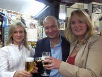 Imagen que muestra a Elena, Carlos y una amiga, tomándose un descanso después de la jornada de trabajo. Los tres están brindando en un bar con una bebida en la mano.
