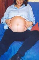 Mujer embarazada mostrando su barriga de ocho meses.