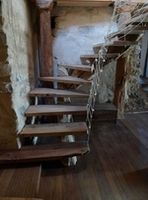 Escalera de madera que gira 90 grados en la que los peldaños formados por tablones apoyan sólo sobre una viga central.