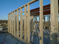 Imagen de una estructura de madera que constituye el entramado de la pared de una casa en la que se ven varios montantes que soportarán un esfuerzo de compresión.