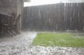 Imagen en la que se ve un patio de madera sobre el que llueve fuertemente.