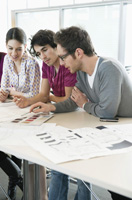 Imagen de tres personas en una oficina hablando sobre un proyecto y mirando planos.