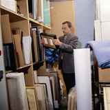 Imagen de un hombre en una sala con una librería llena de documentos.