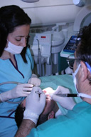 Primer plano de intervención bucodental con odontólogo y técnico colaborando.