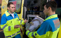 Junto a una ambulancia dos técnicos de emergencias, con su indumentaria de trabajo, hablando.