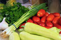 Se observan en la imagen diferentes vegetales: ajos tiernos, tomates, pimientos, perejil, ajos...