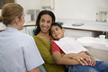 Fotografía en la que se aprecia un niño con su madre, ambos sentados en el sillón dental.