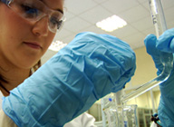 Primer plano de una técnico sanitaria trabajando con guantes y gafas de protección.