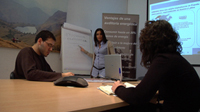 Imagen de un grupo de personas trabajando juntas con una pizarra de papel y con un proyector.