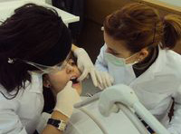 Claudia, recién titulada, y Elena, técnica con experiencia, realizando una exploración dental a un paciente en el centro de salud.