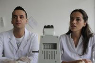 Carlos y Susana escuchando a su tutor ante un microscopio.