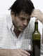 Un hombre con aspecto de alcoholizado junto a una botella de vino.