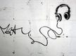 Grafiti sobre una pared blanca de unos auriculares, cuyo cable forma la firma. 