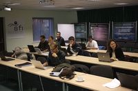 Conjunto de trabajadores reunidos con sus portátiles en una sala, recibiendo formación.