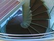 Fotografía que muestra la perspectiva superior de una escalera de caracol. La escalera de caracol es aparentemente metálica.