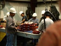 Fotografía en la que se pueden ver varios trabajadores en una cadena de producción de una fabrica.