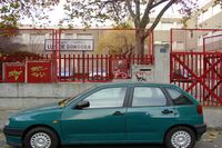 Fotografía en la que se aprecia un coche de color verde aparcado en la calle, justo en frente de un centro infantil.