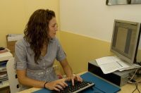 María sentada, trabajando escribiendo con un ordenador, mirando a la pantaalla y tecleando..