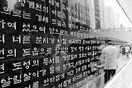 Se ve una pared en una calle, con muchas líneas o flujos de escritura en caracteres parecidos a los japoneses o chinos.