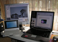 Foto que muestra en primer plano un portátil y un notebook abierto y una pantalla TFT sobre un escritorio.